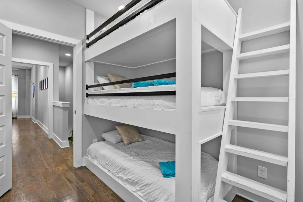 A cozy bedroom with stylish bunk beds featuring blue accents and wooden flooring. The playful arrangement suggests a welcoming environment for groups or friends, perfect for sleepovers, late-night chats, or fun group stays.