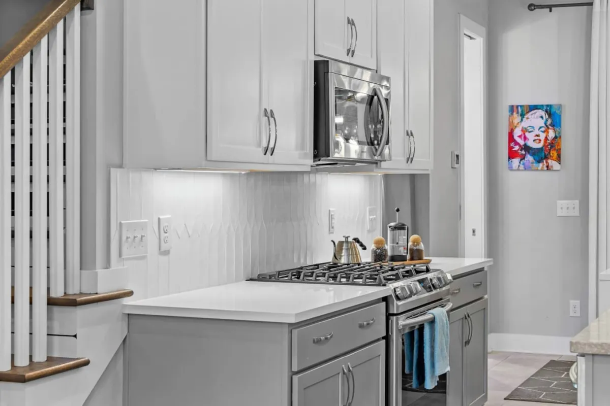 A welcoming kitchen with stainless steel appliances, white cabinetry, and colorful artwork. The space is designed for socializing, preparing meals, or sharing stories over dinner—ideal for gathering after a night out.